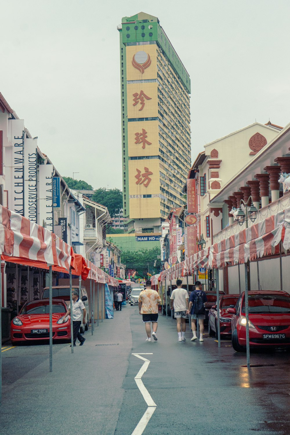 a group of people walking down a street next to tall buildings