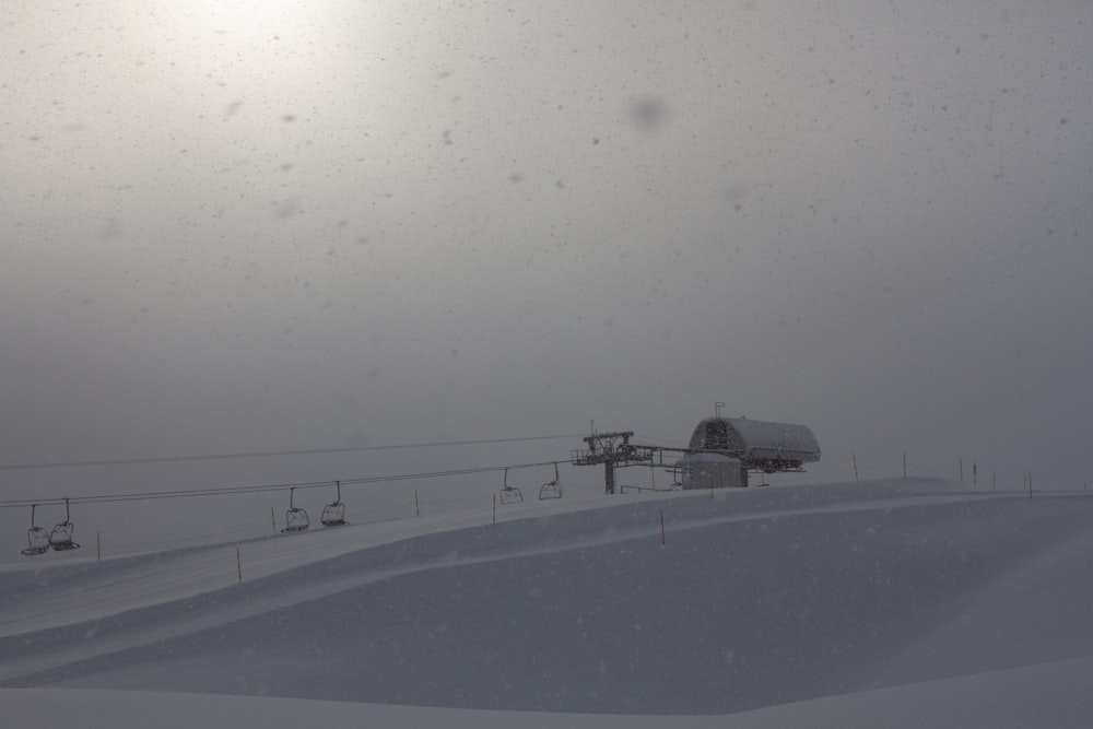 a snow covered ski slope with a ski lift in the distance