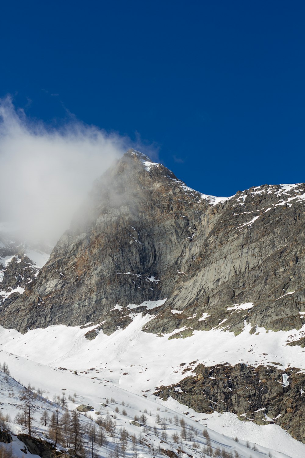 a snow covered mountain with a cloud in the sky