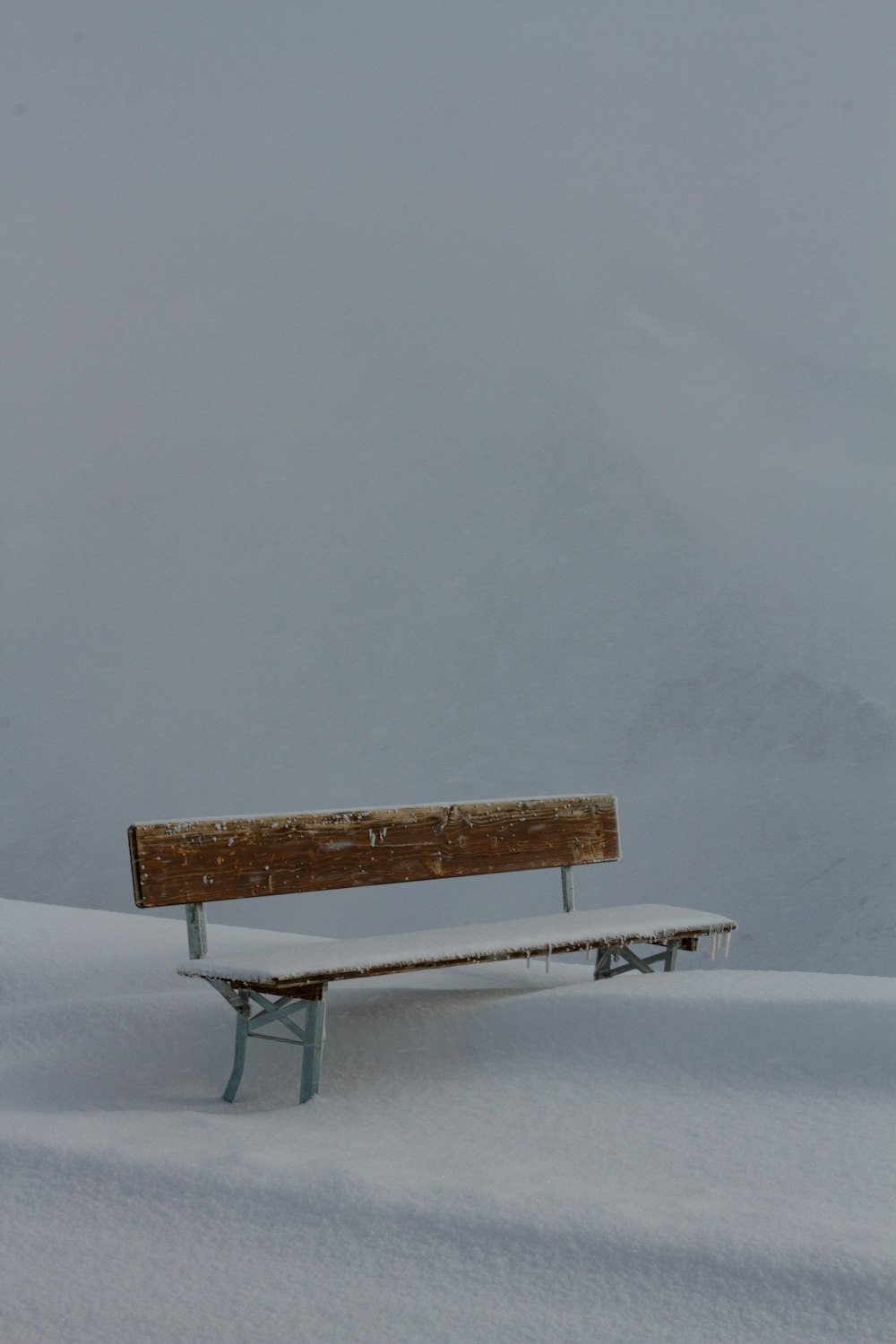 a wooden bench sitting in the middle of a snow covered field