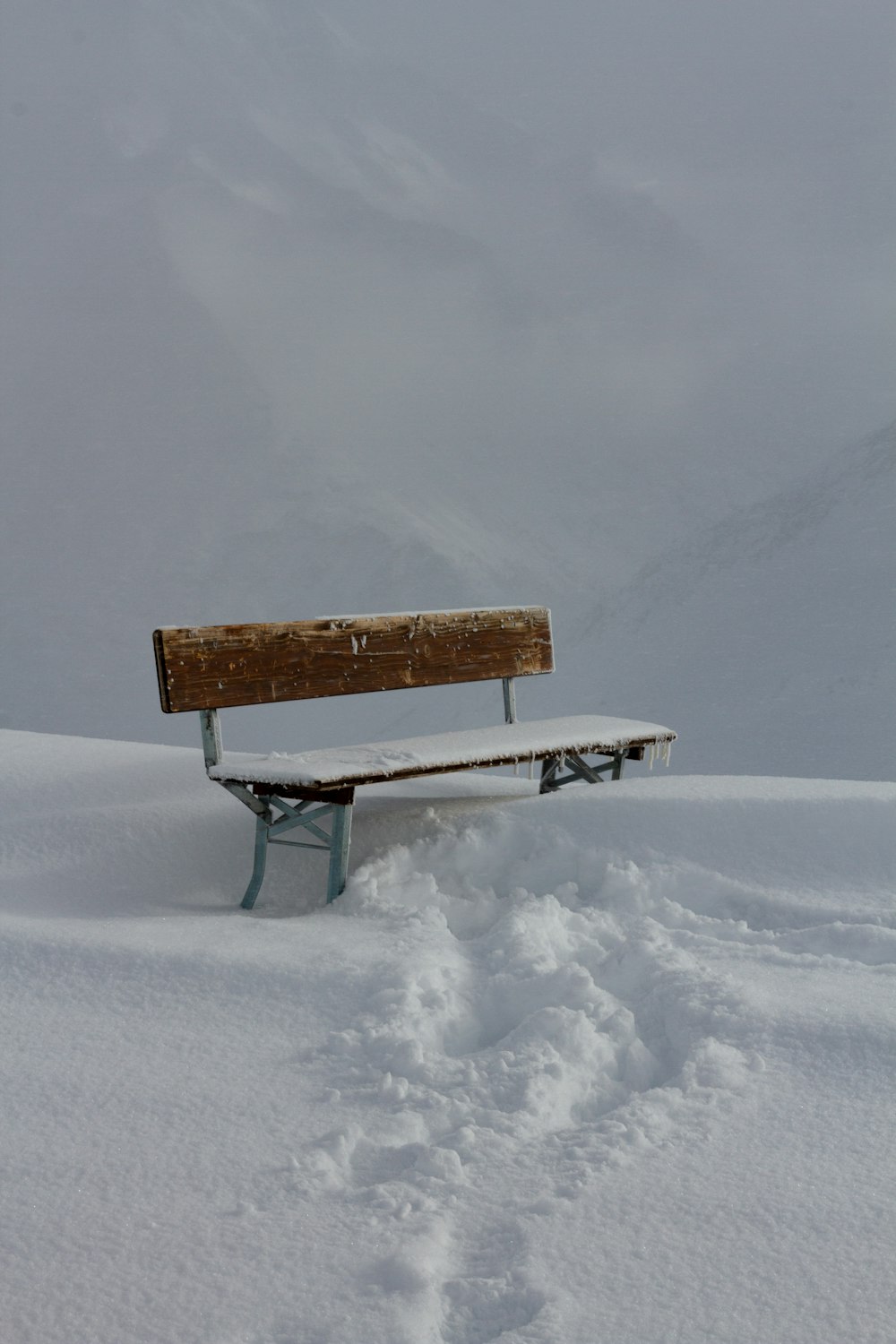 a bench sitting in the middle of a snow covered field