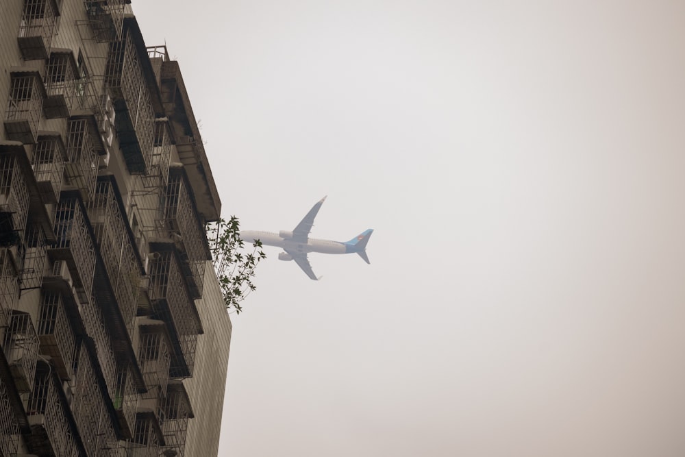 an airplane flying in the sky over a tall building