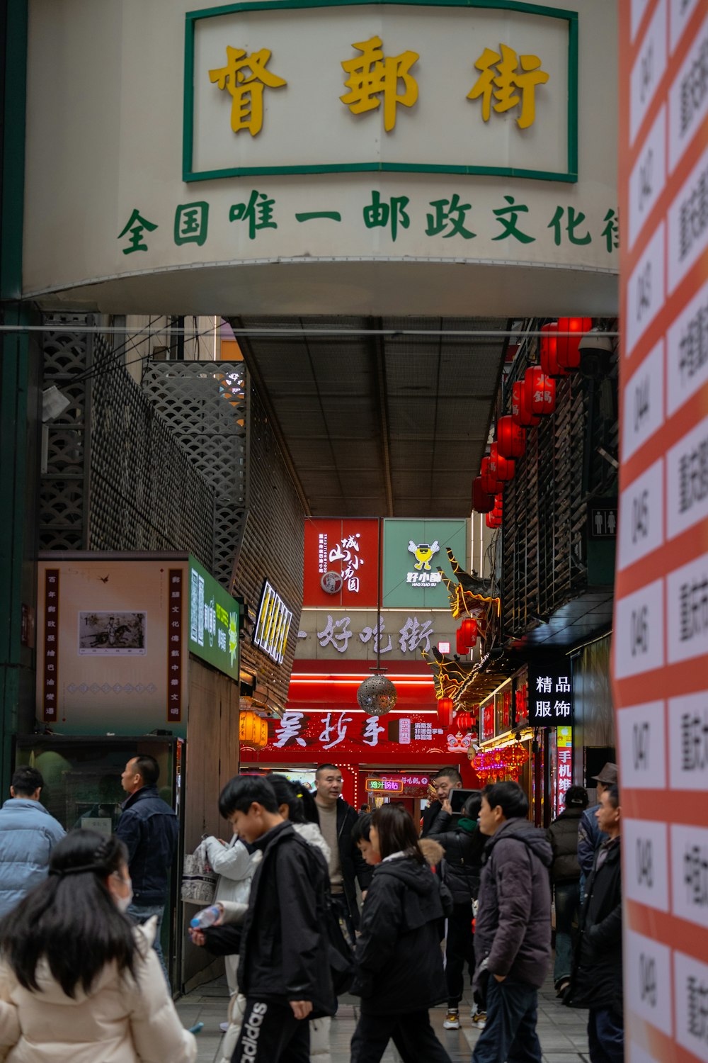 a group of people walking down a street next to tall buildings