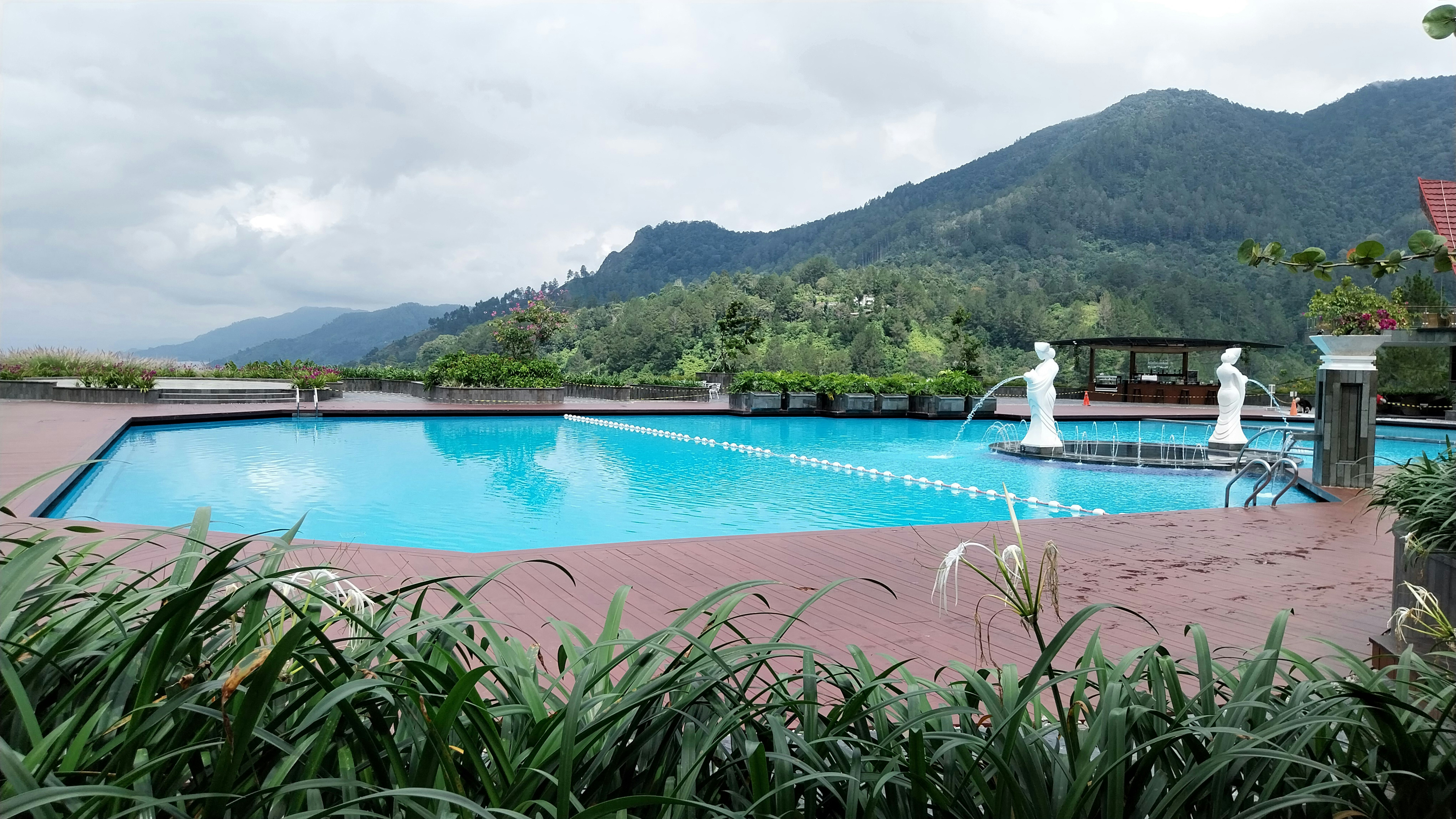 Outdoor swimming pool surrounded by mountain forest with clear blue water