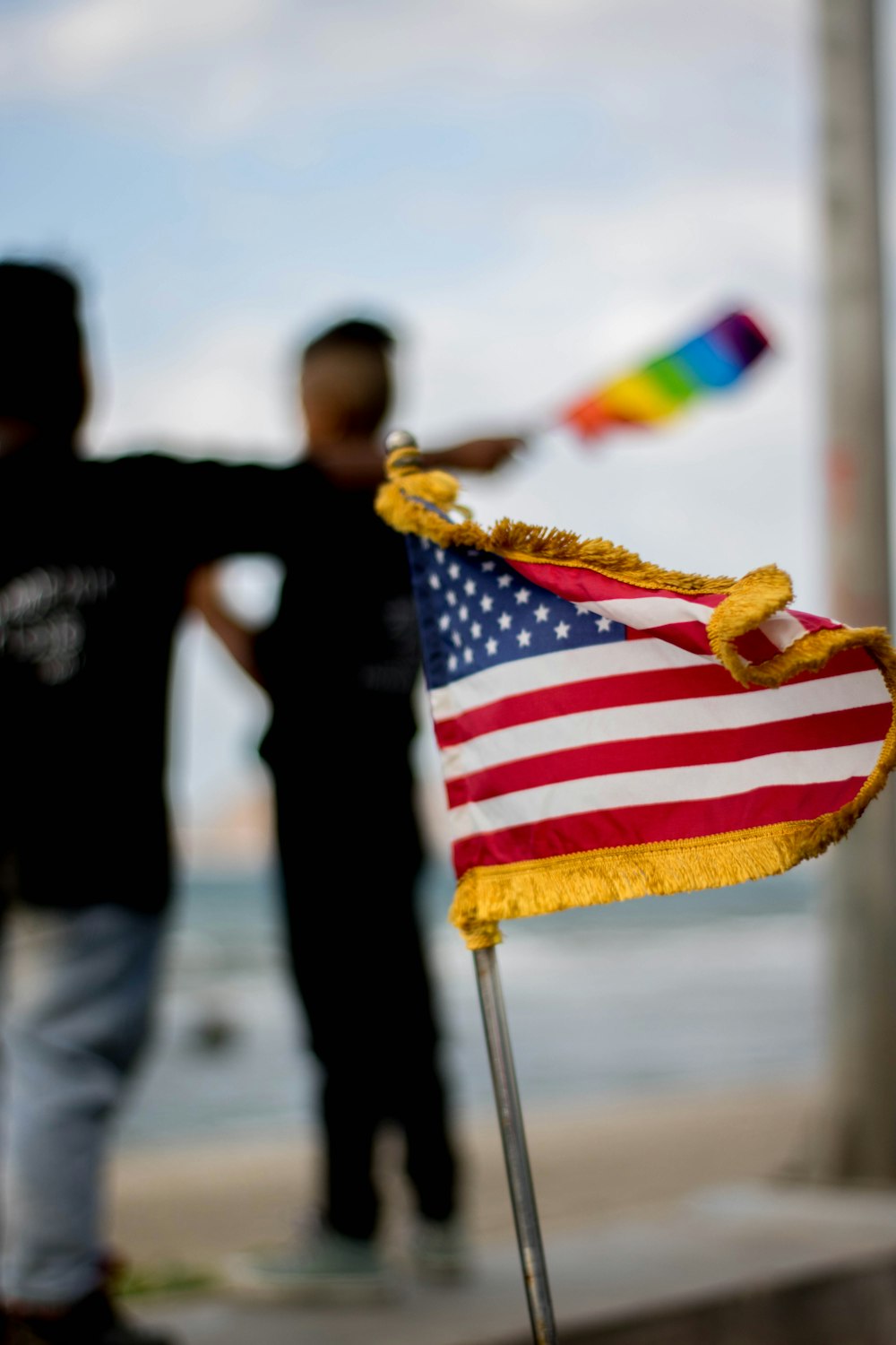 Uma pequena bandeira americana em um bastão com um homem ao fundo