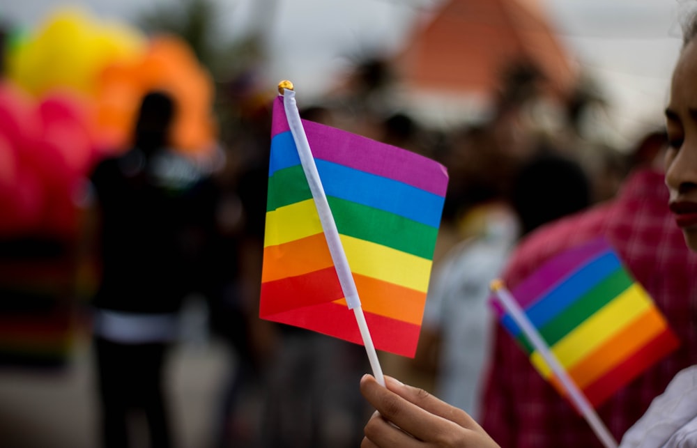 a young girl holding a rainbow colored flag