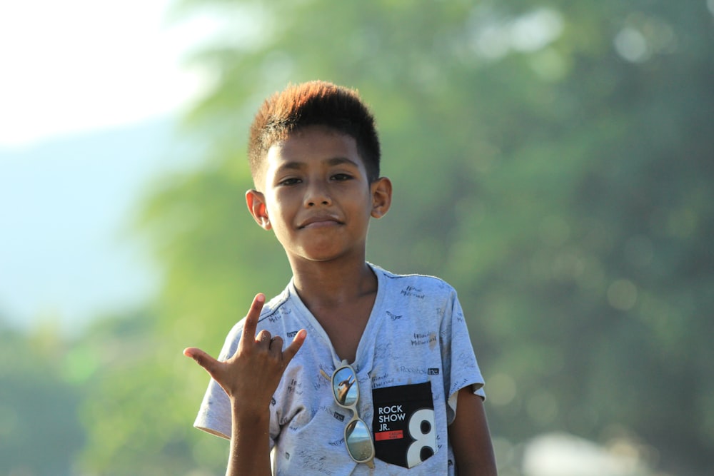 um menino fazendo um sinal de paz com as mãos