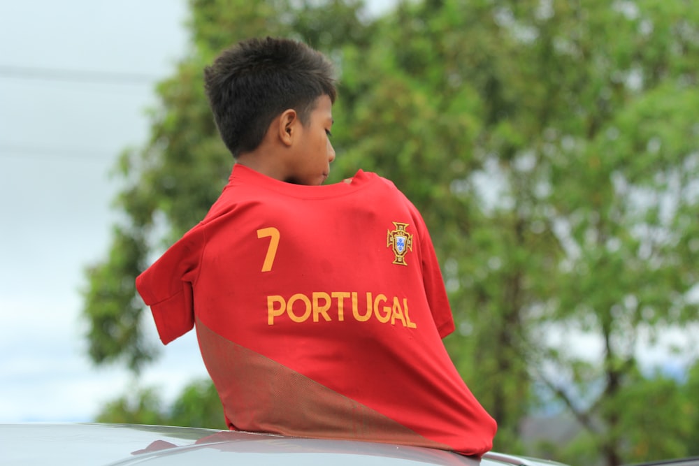 a young boy sitting on top of a car