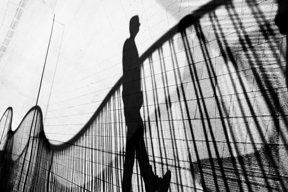 a shadow of a man walking across a bridge