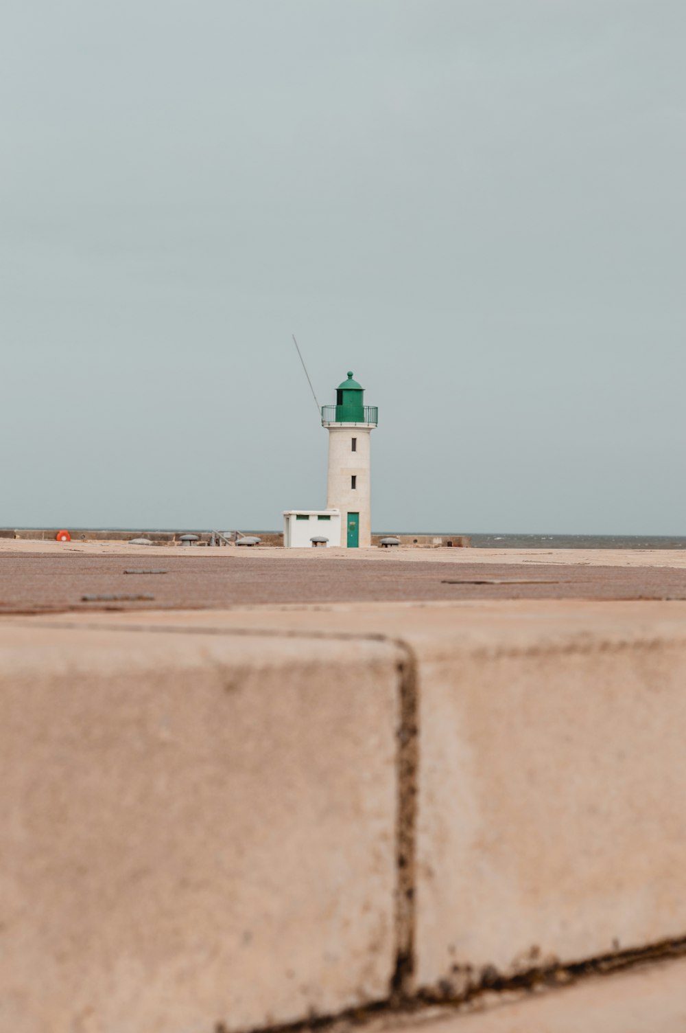 una casa faro seduta in cima a una spiaggia sabbiosa