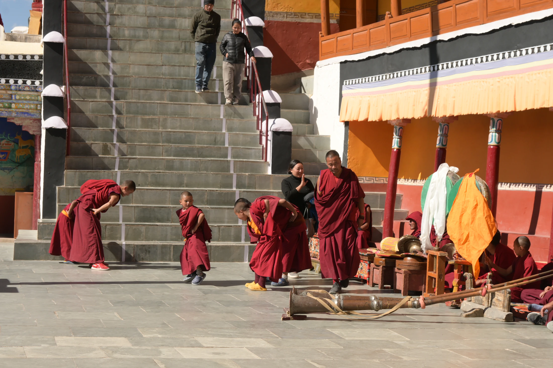 Young monks in maroon robes on the steps of a Ladakhi monastery courtyard