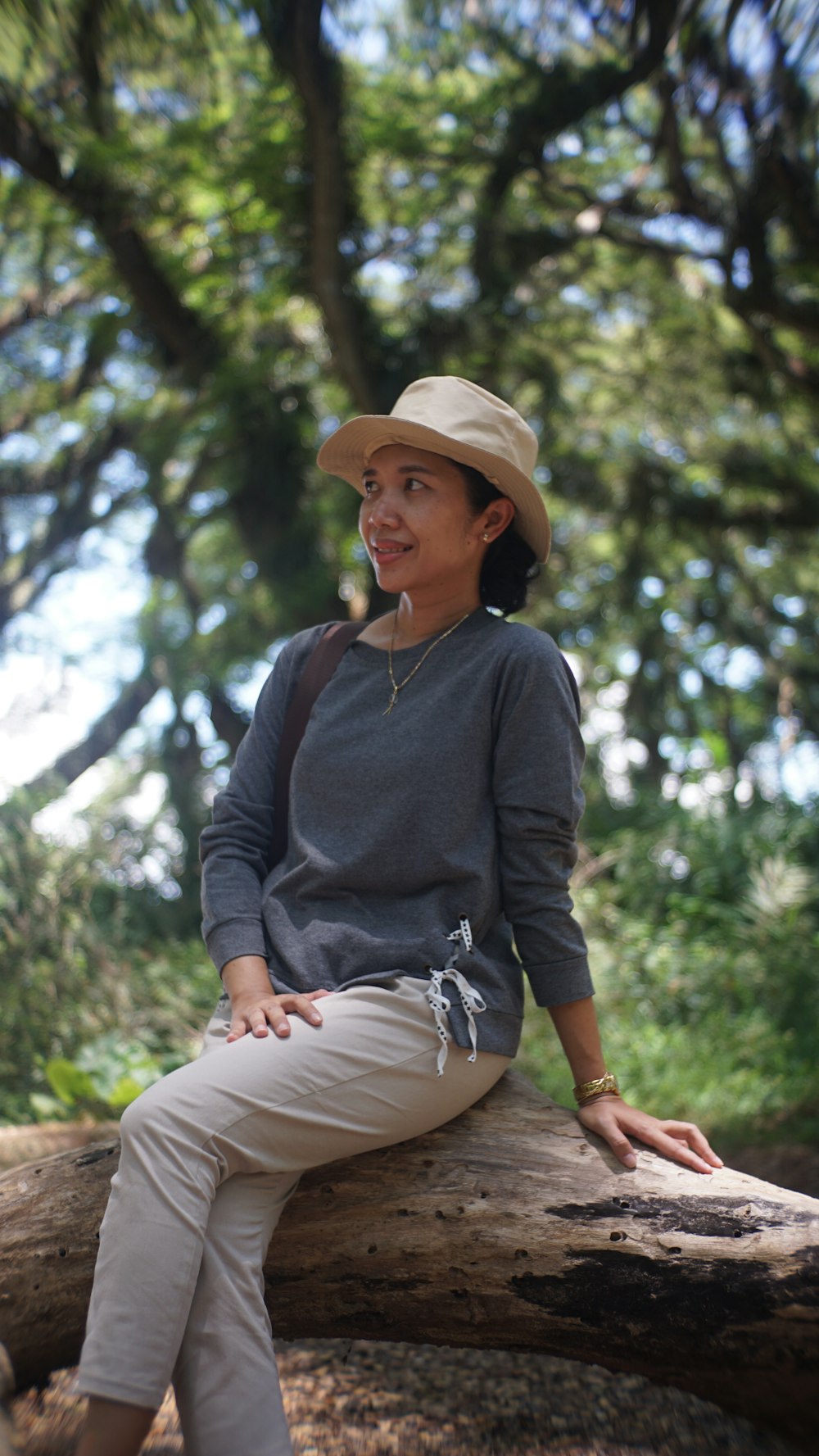 a woman sitting on a log in the woods