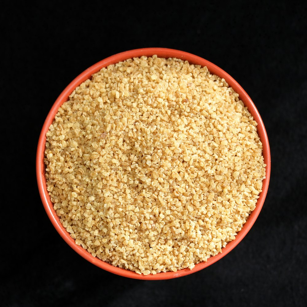 a bowl of sesame seeds on a black background