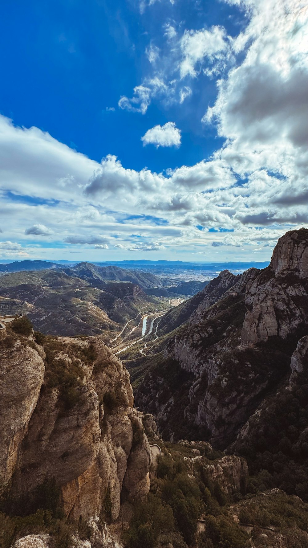 a scenic view of a valley and mountains under a cloudy sky