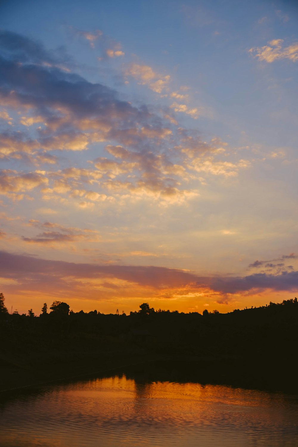 a sunset over a body of water with trees in the background