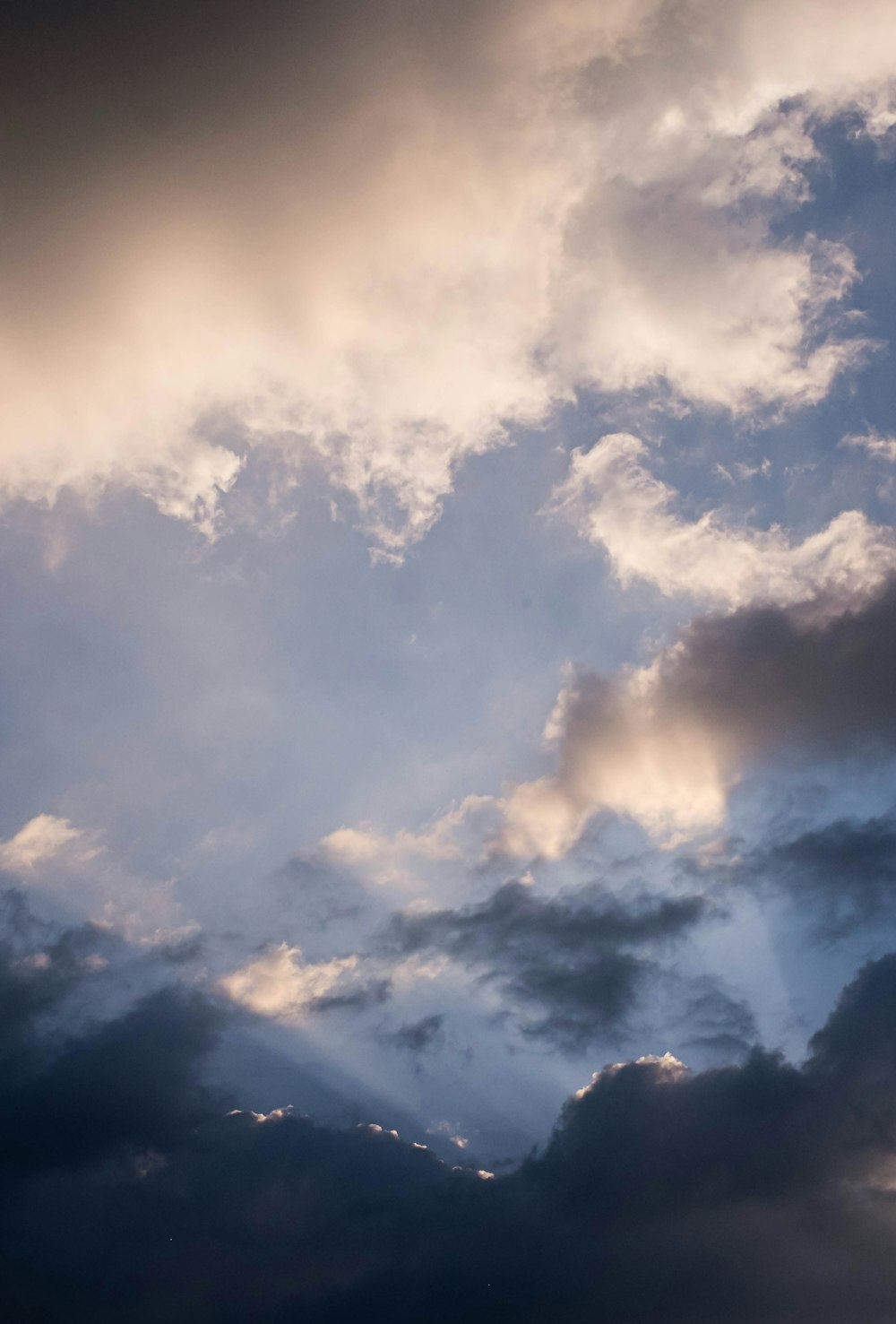 a plane flying through a cloudy blue sky