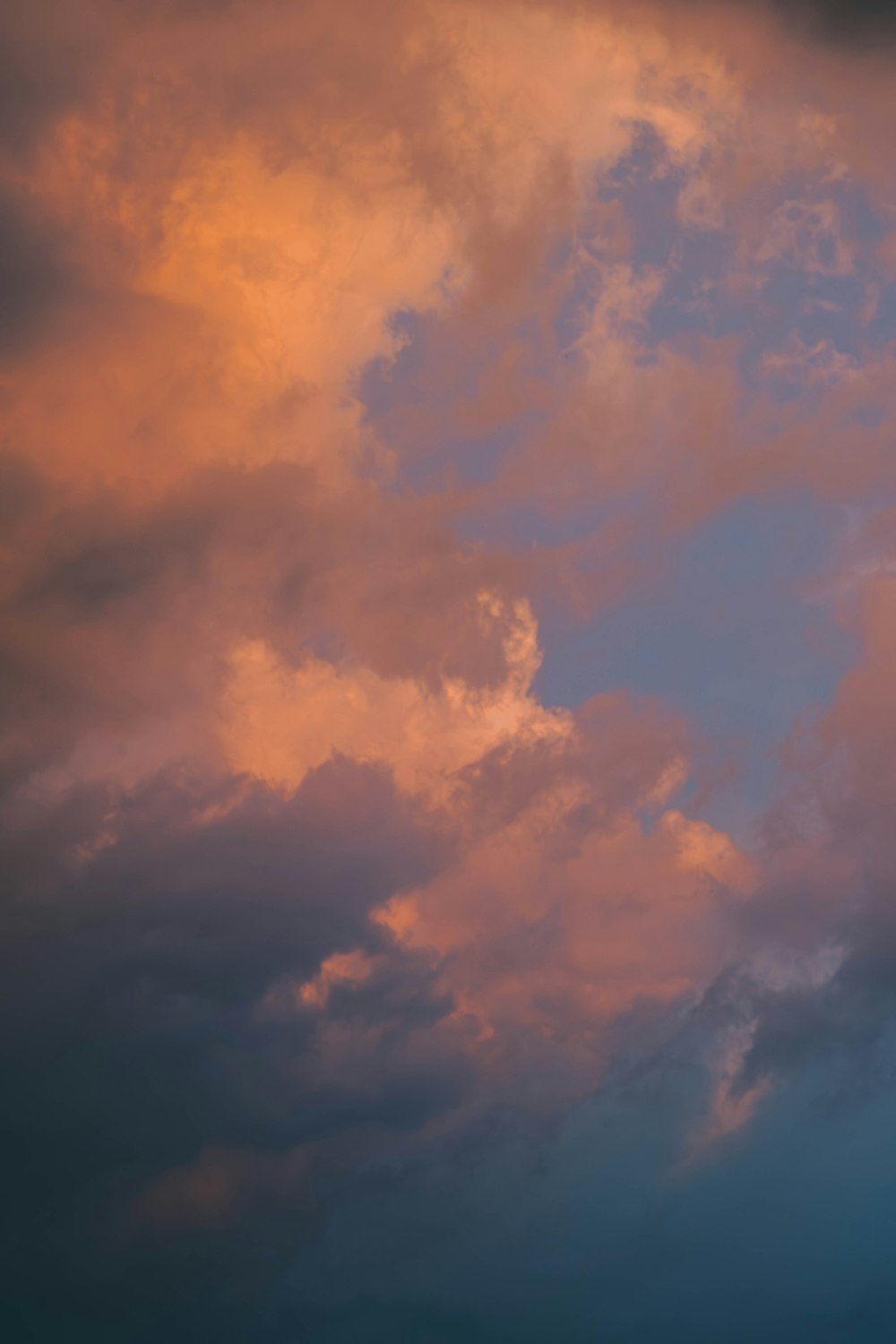 a plane flying through a cloudy sky at sunset