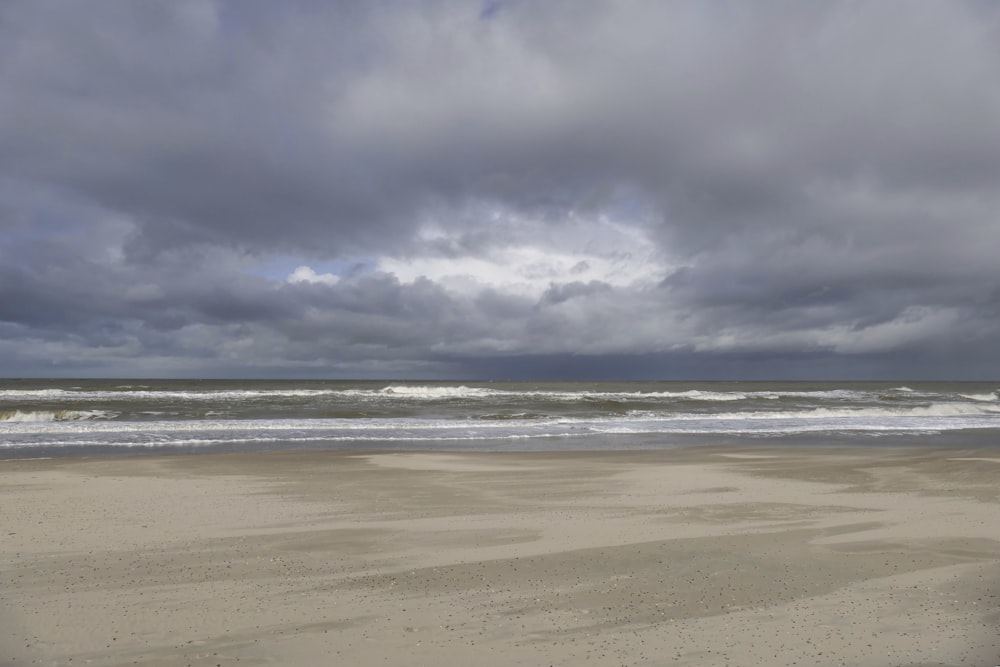 a cloudy day at the beach with a surfboard in the foreground