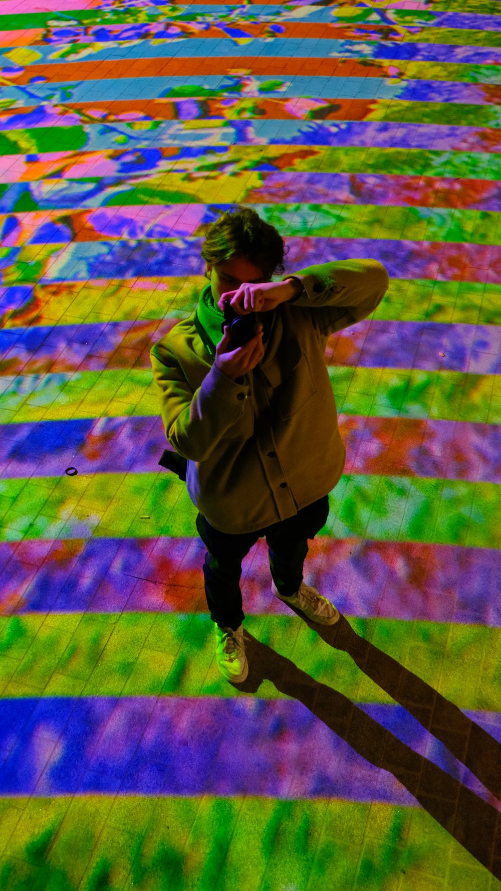 a person standing on a colorful floor with a coat on