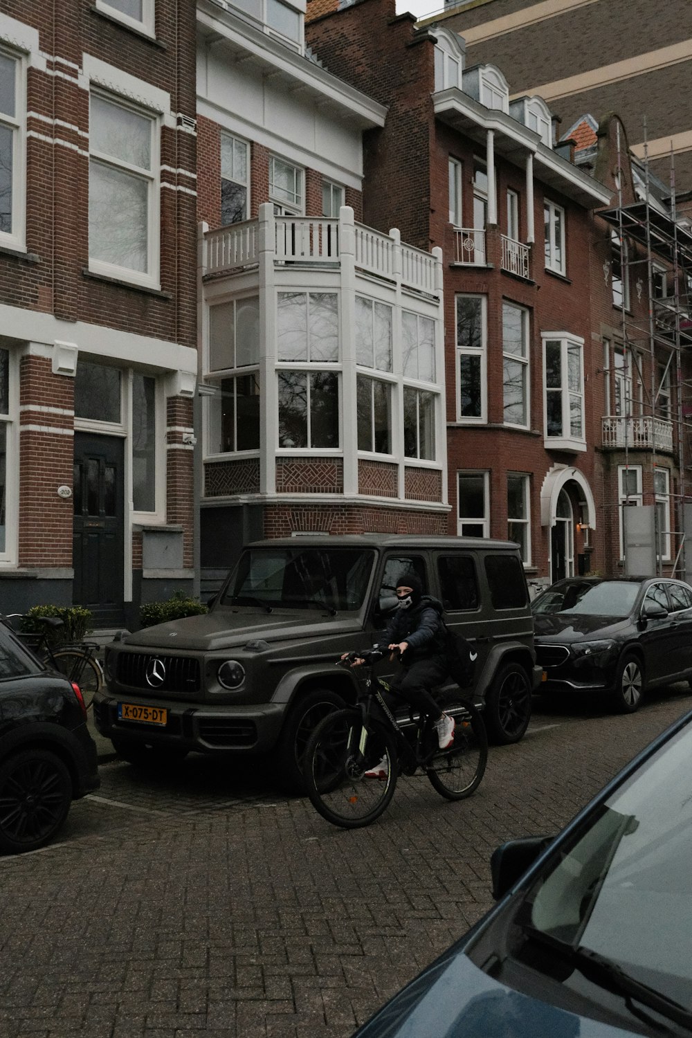 a man riding a bike down a street next to parked cars