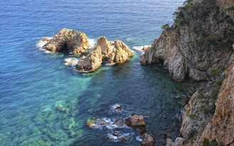 a body of water next to a rocky cliff