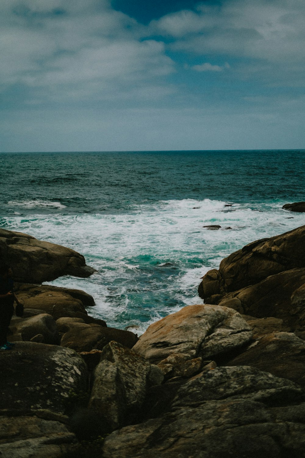 a person standing on rocks near the ocean