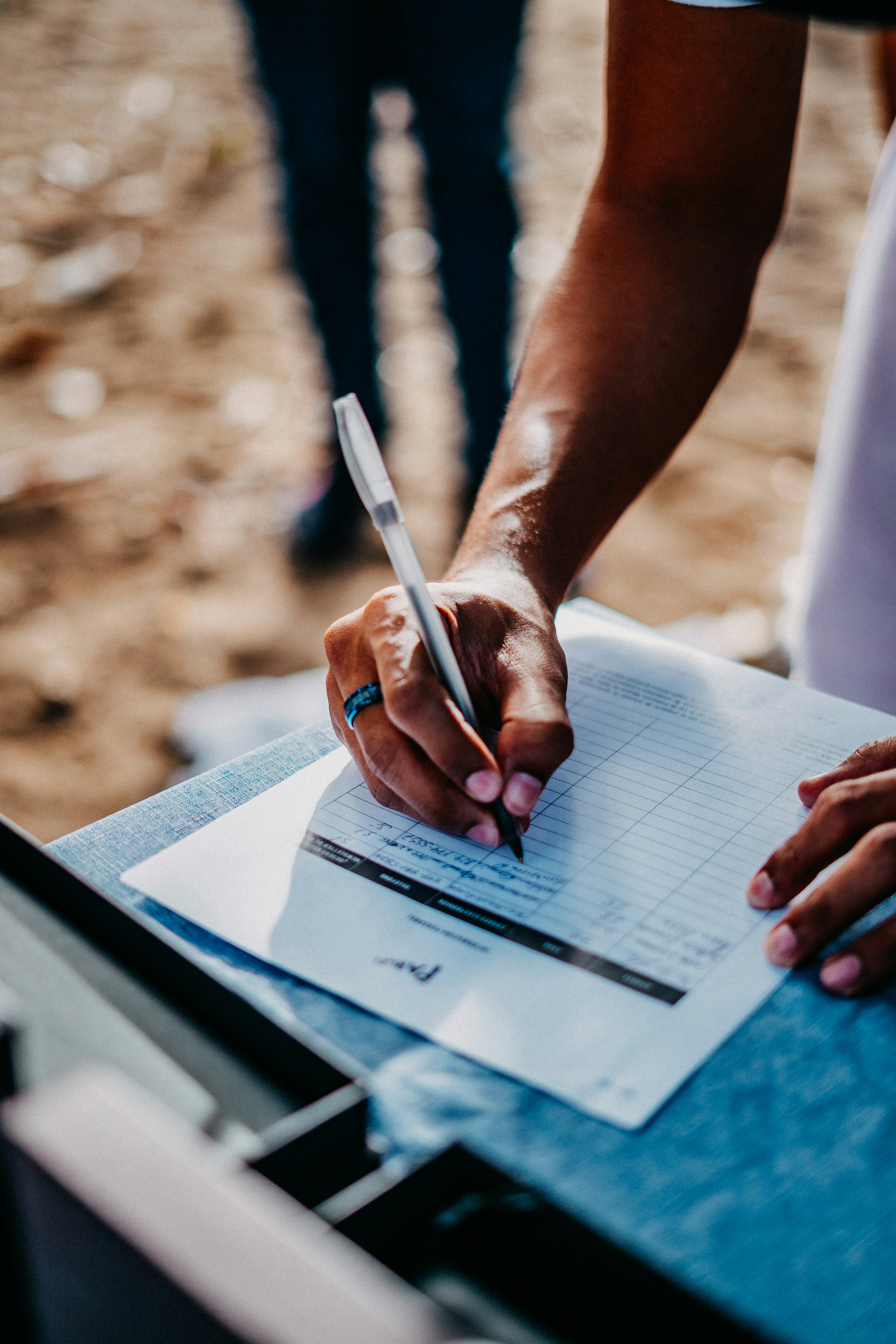 a person holding a pen and writing on a piece of paper