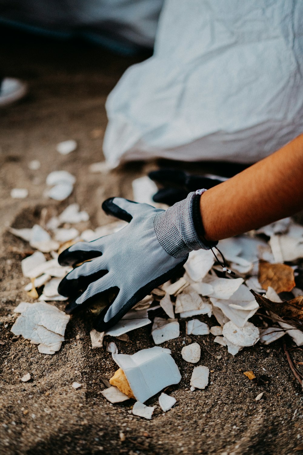 a person with a glove on picking up a pile of broken glass