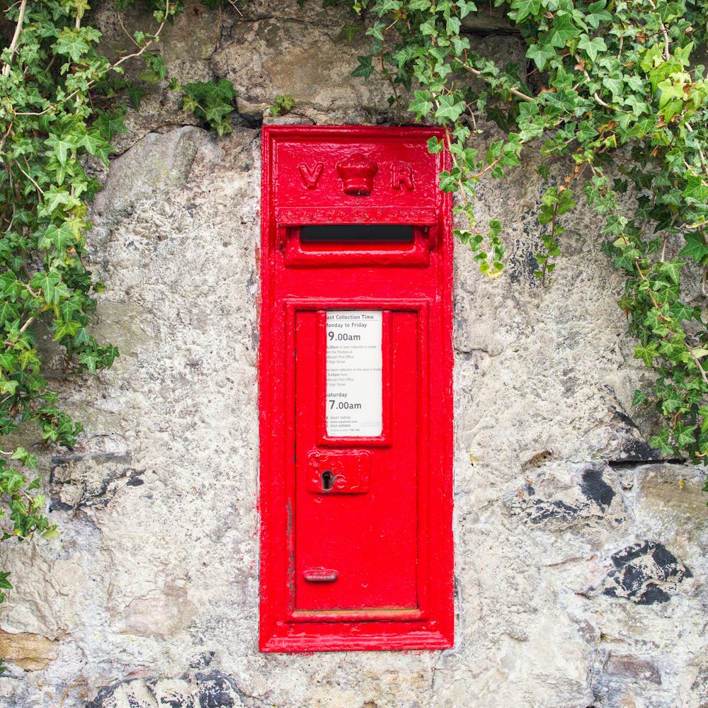 a red post box sitting on top of a stone wall