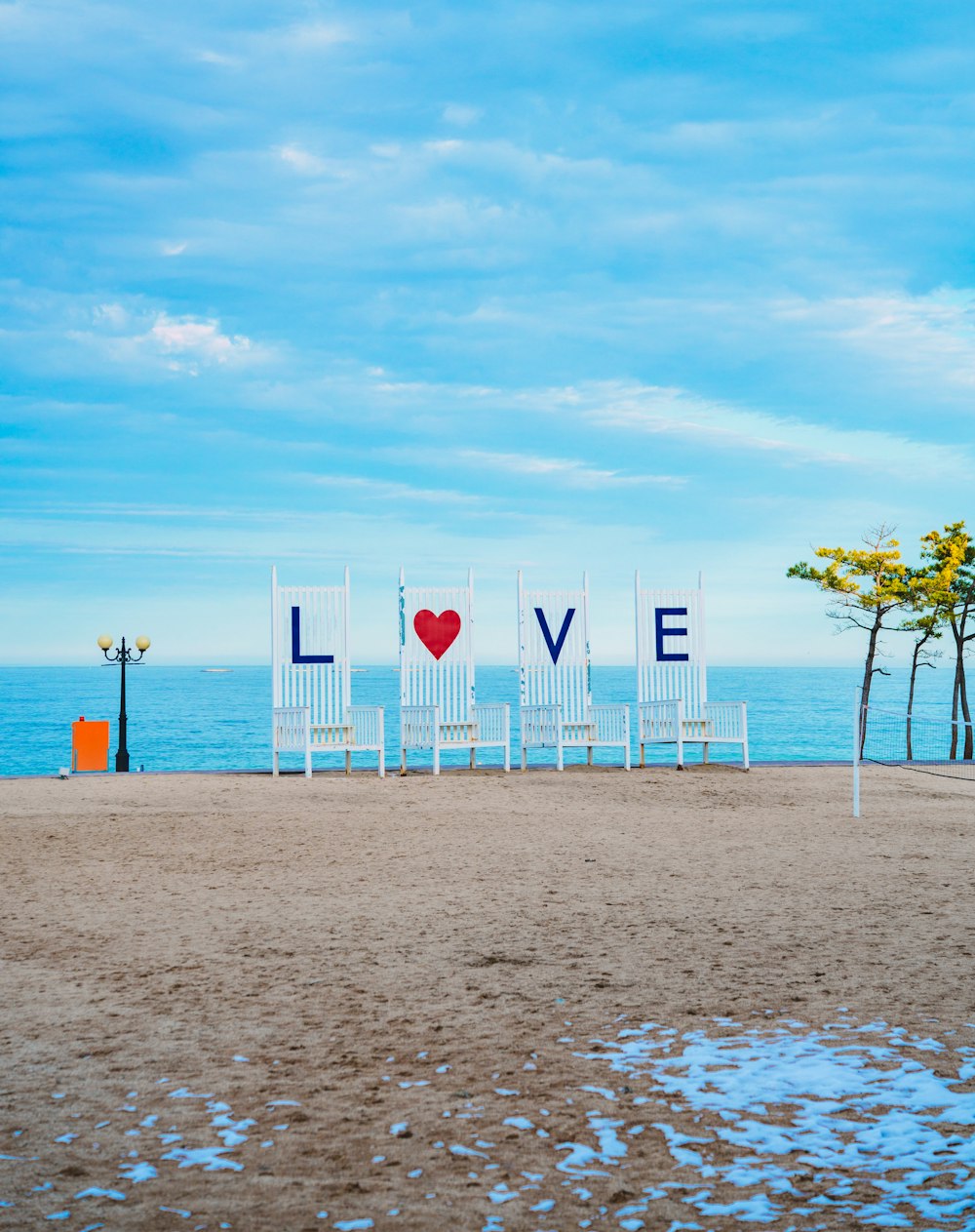 a couple of white chairs sitting on top of a sandy beach