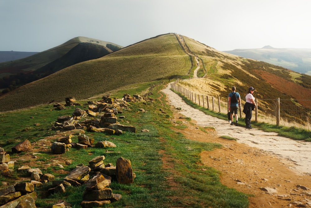 a couple of people walking down a dirt road