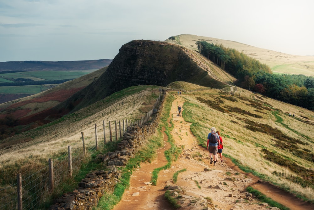 a couple of people walking down a dirt road