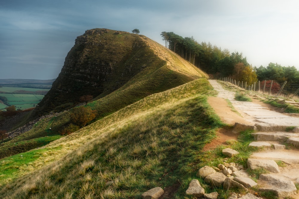 un camino de piedra que conduce a una colina cubierta de hierba
