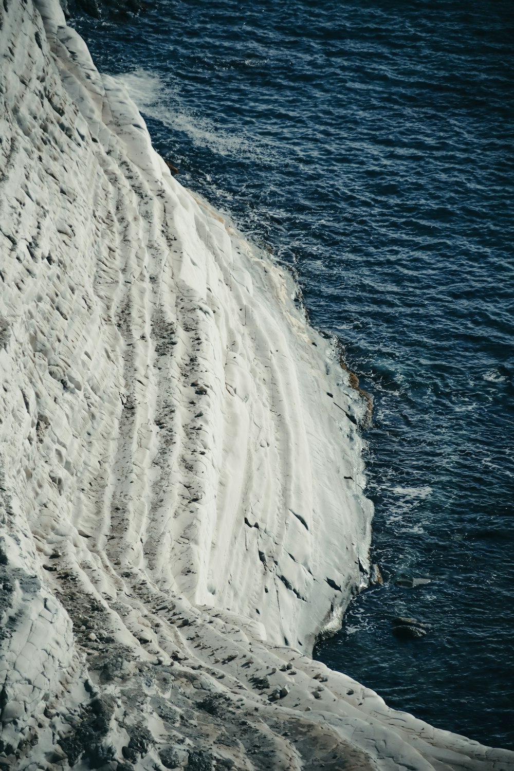 a person walking on a snow covered hill next to a body of water