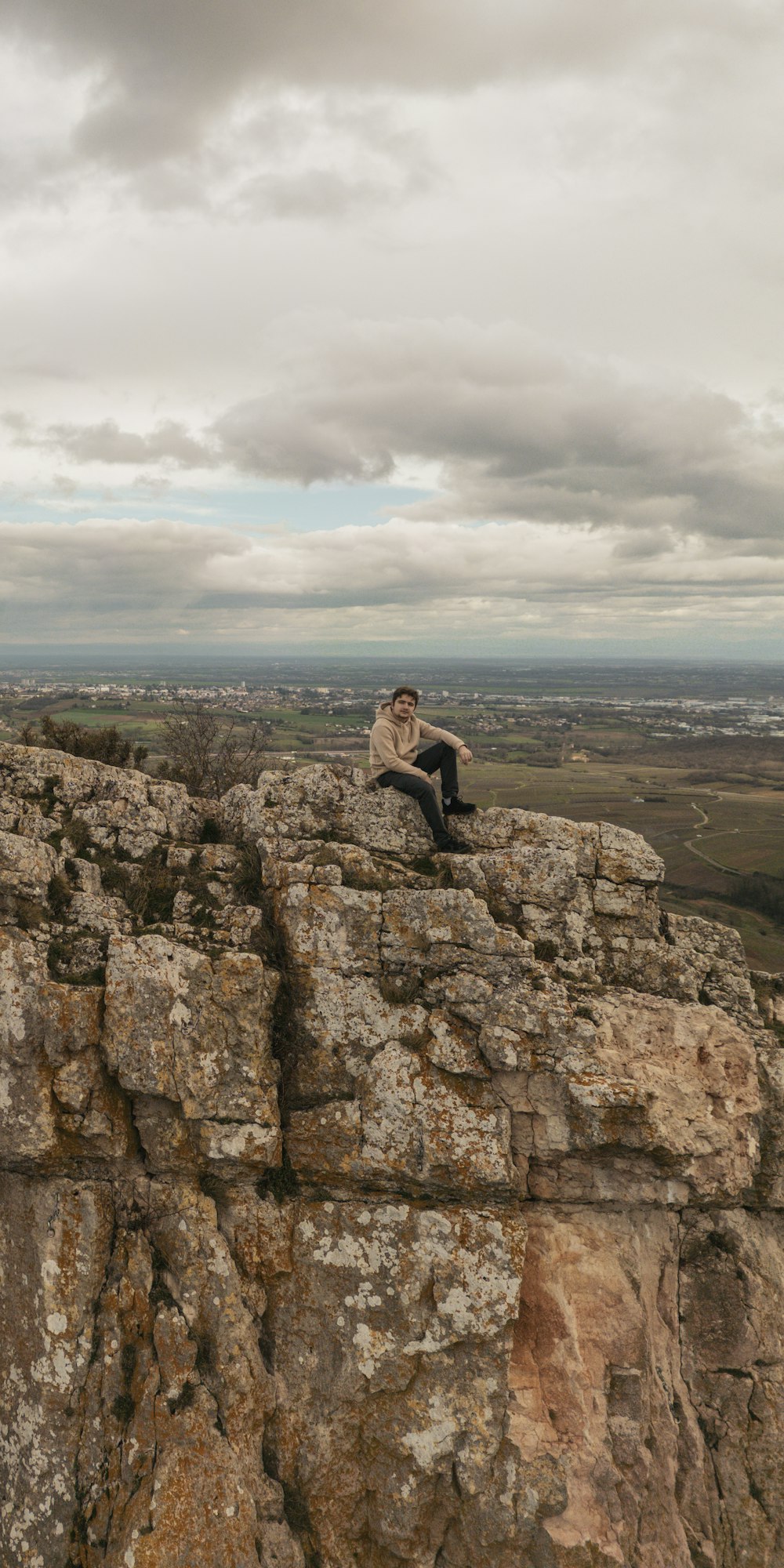 un homme assis au sommet d’une falaise rocheuse