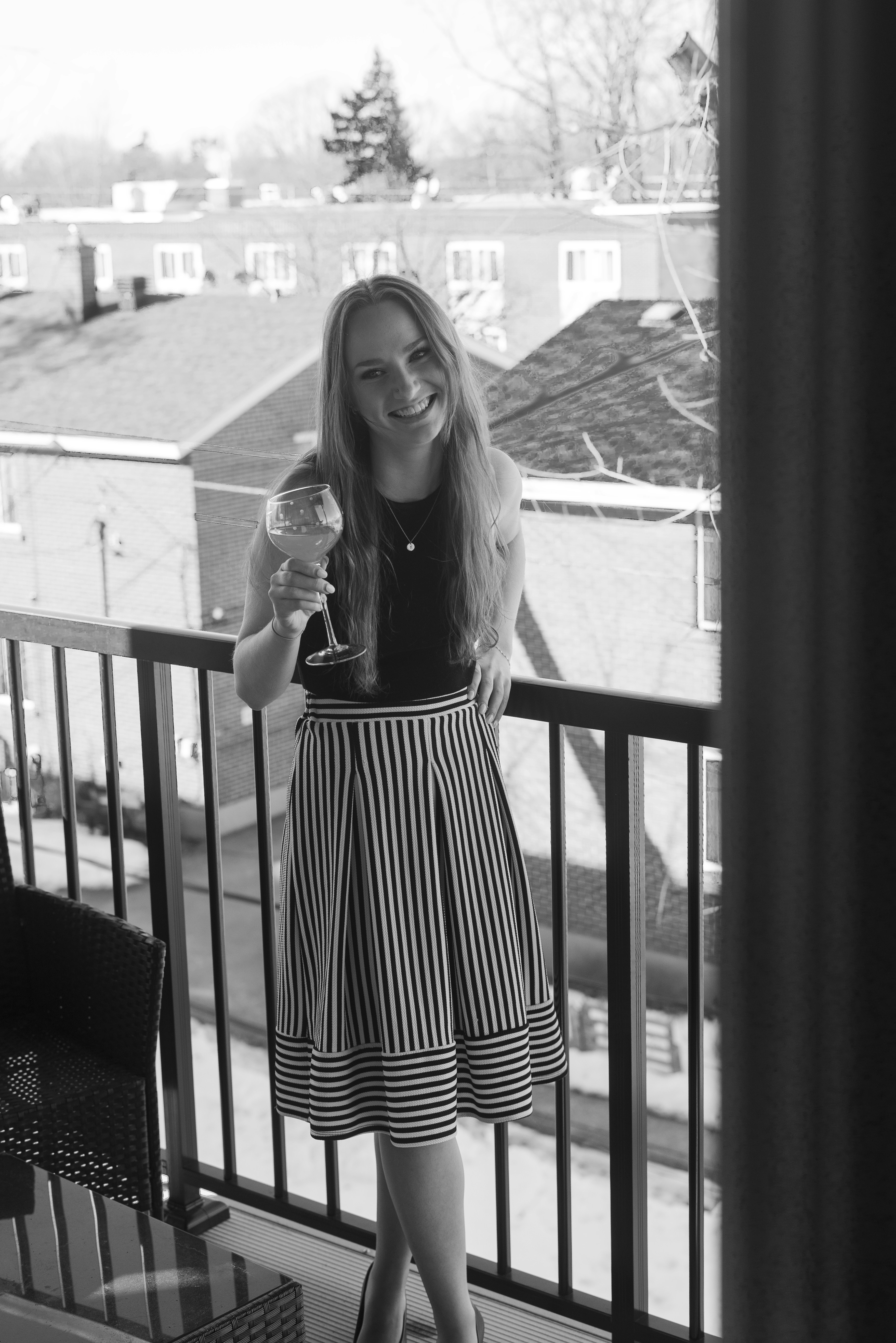 a woman standing on a balcony holding a wine glass