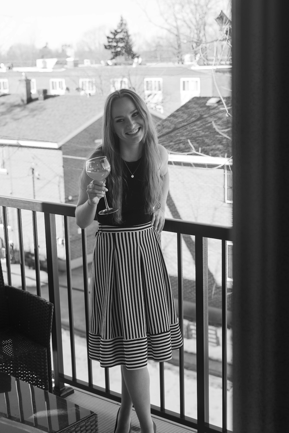 a woman standing on a balcony holding a wine glass