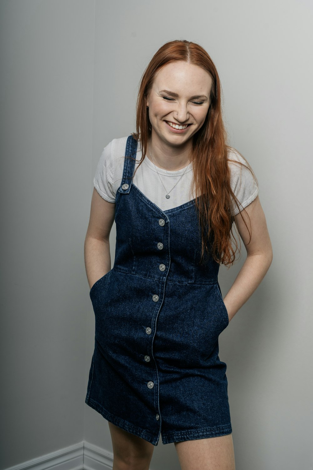 a woman with red hair wearing overalls and smiling