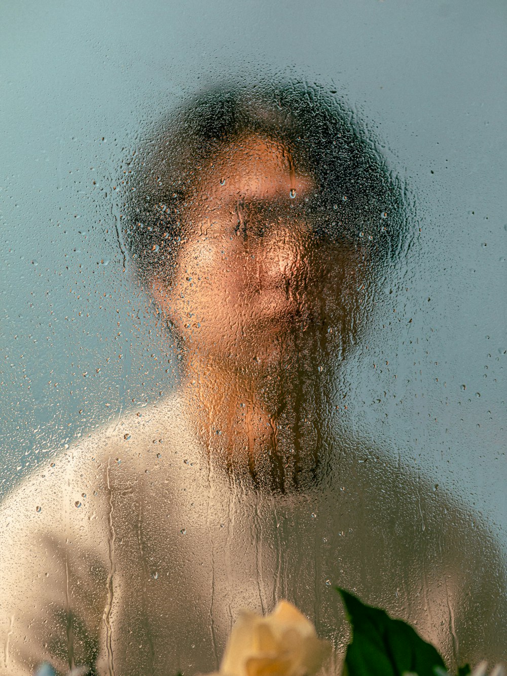 a man standing in front of a window covered in rain
