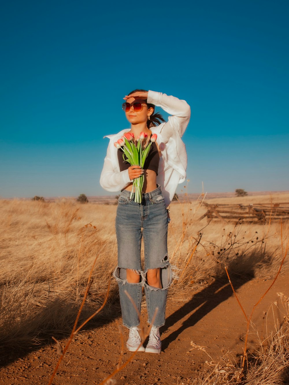 una donna in piedi in un campo con in mano un mazzo di fiori