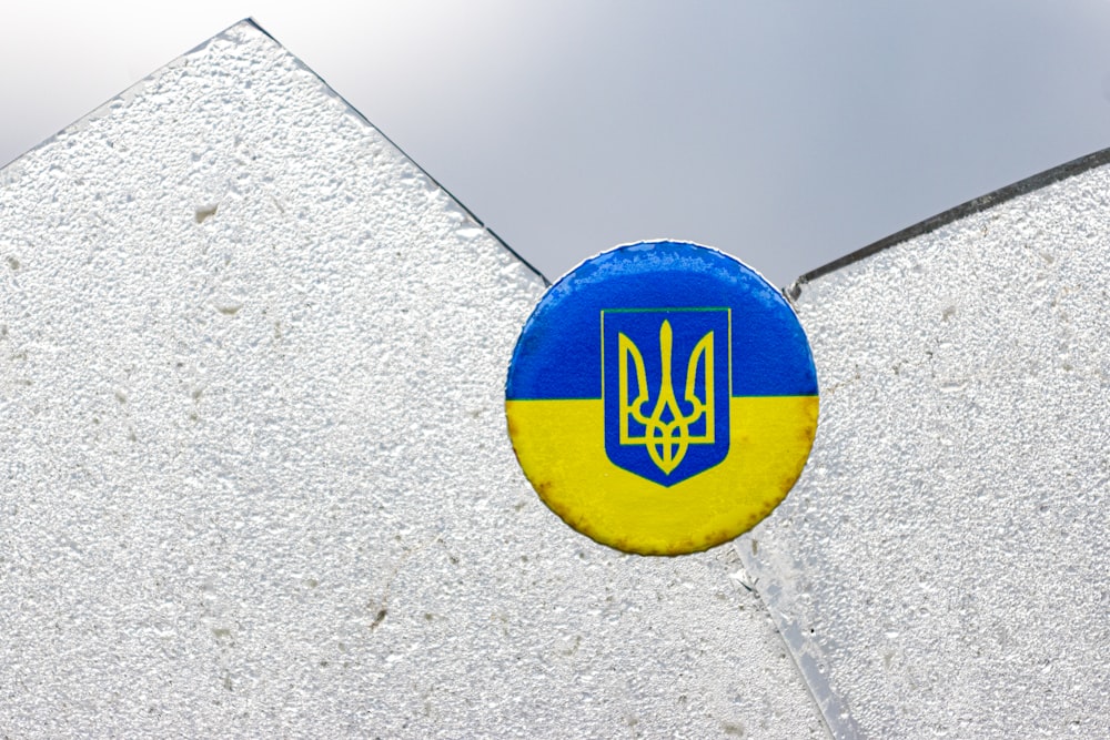 a blue and yellow button on a white building