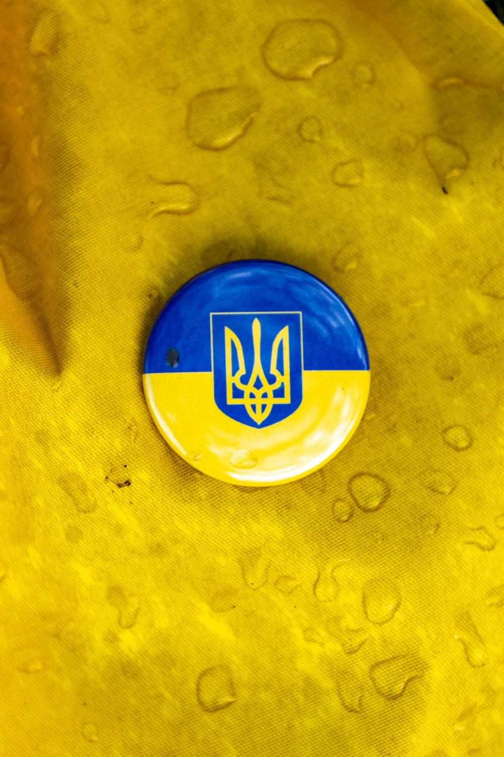 a blue and yellow button sitting on top of a yellow cloth