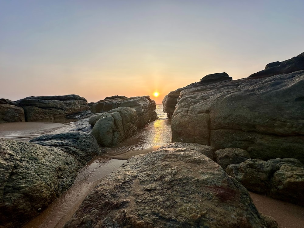 el sol se está poniendo sobre una playa rocosa