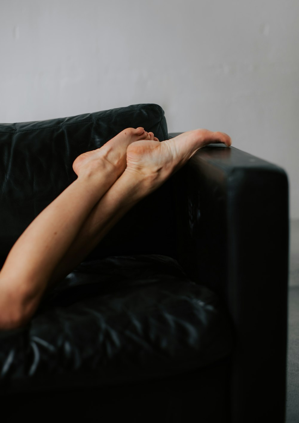 a woman laying on top of a black couch