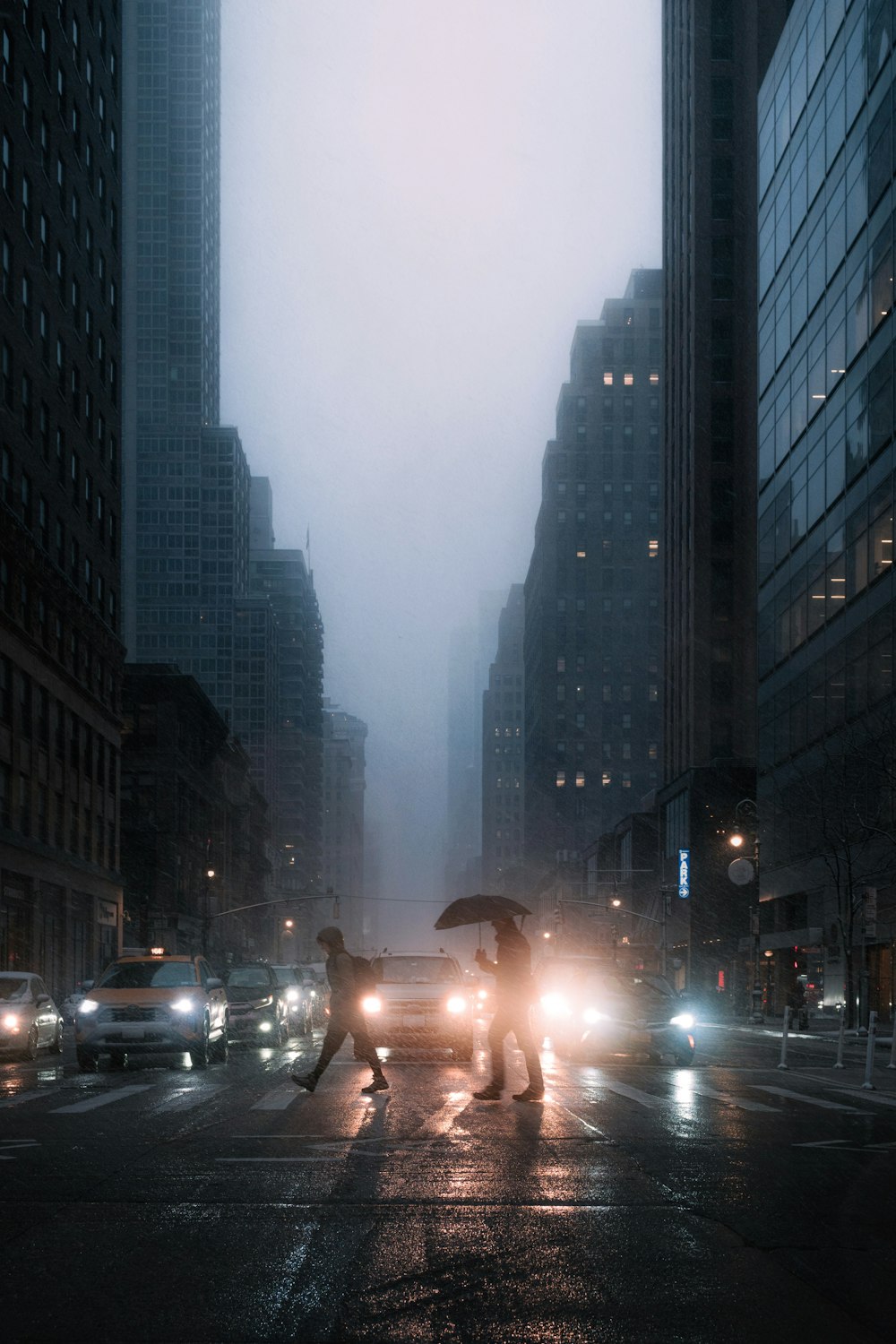 a couple of people crossing a street at night