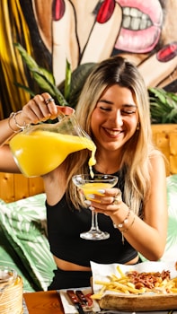 a woman pouring a drink into a glass