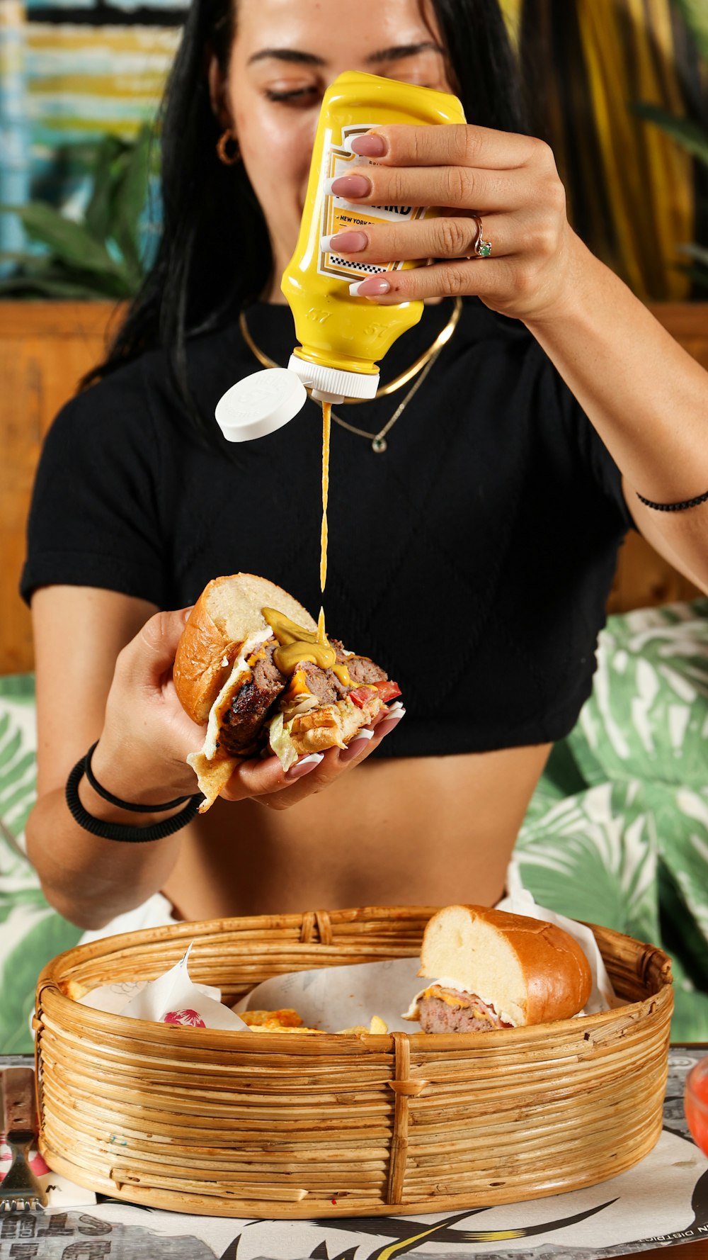 a woman is pouring mustard on a sandwich