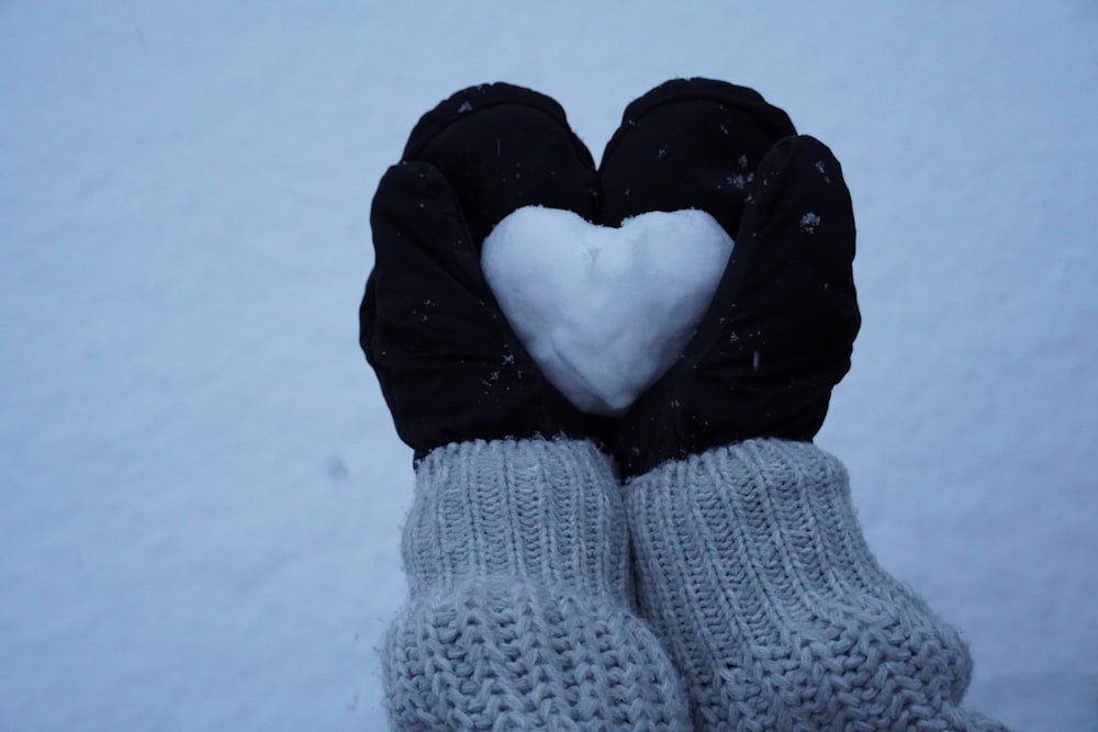 a pair of gloves with a heart on them in the snow
