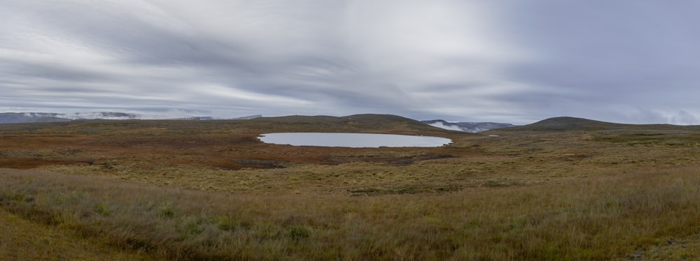 a field with a small lake in the middle of it