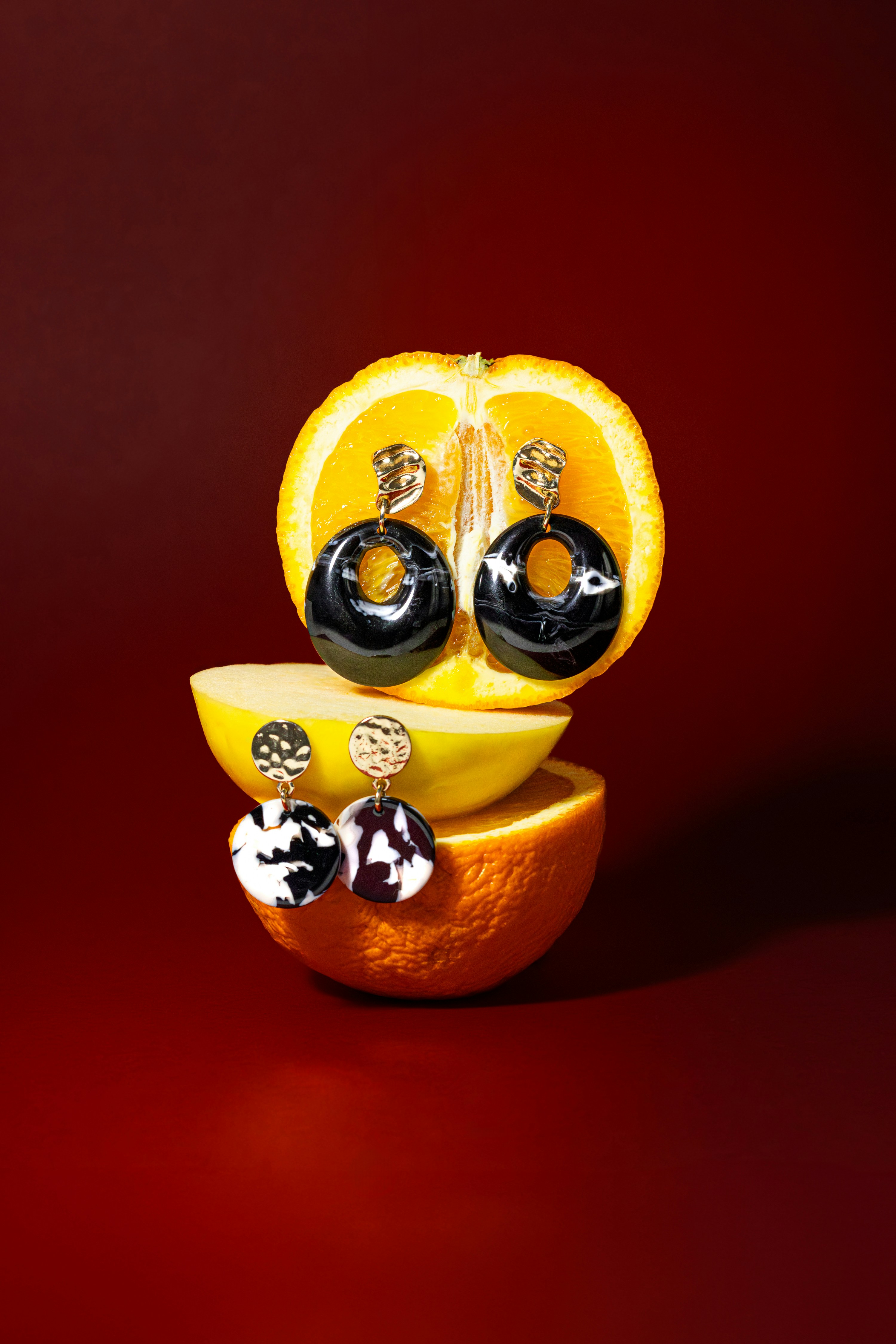 une orange avec une paire de boucles d’oreilles noires et blanches posées dessus
